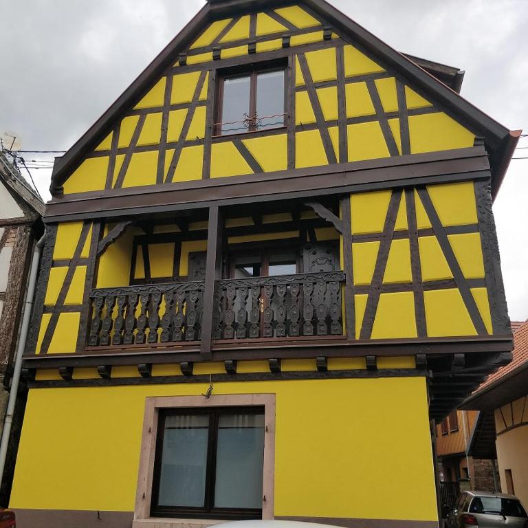 - un bâtiment jaune et noir avec un balcon dans l'établissement Le Familial, à Kintzheim