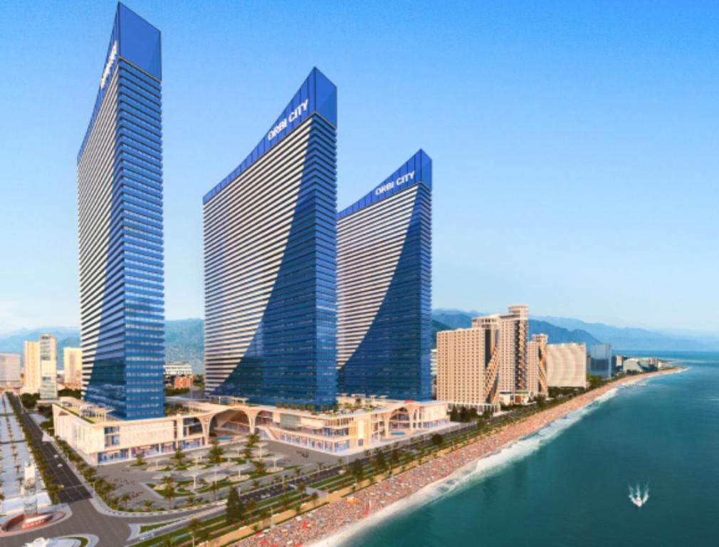 three tall buildings in a city next to the water at Orbi City Sea Side & Sea View Apartments in Batumi