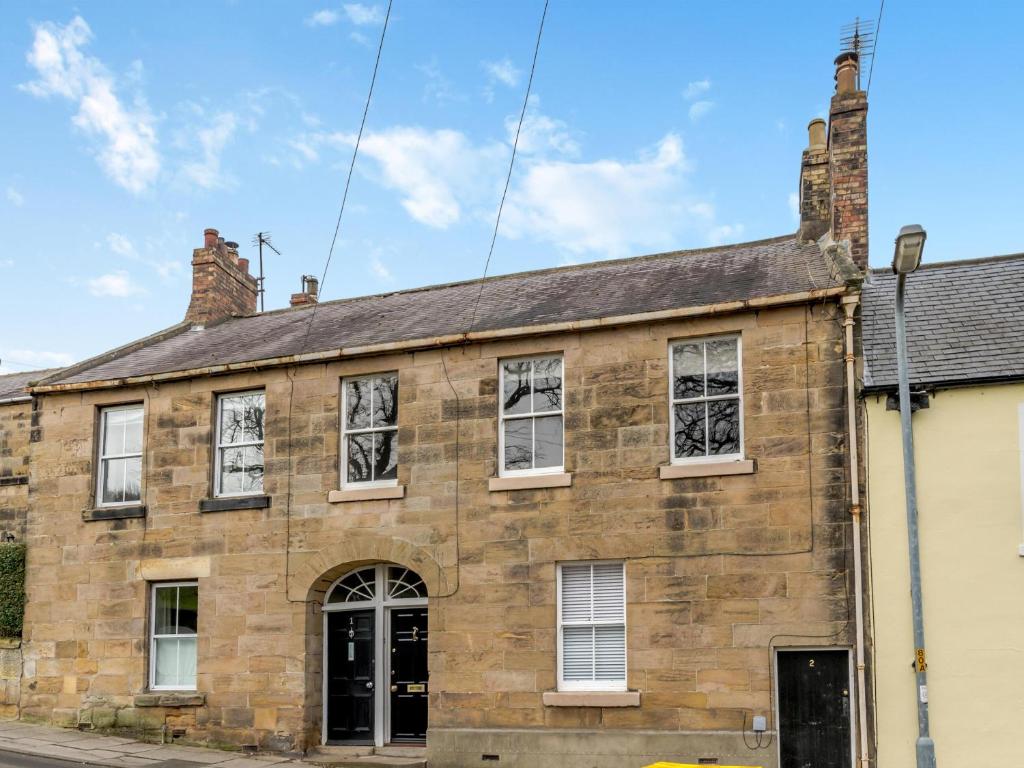 an old brick building with white windows on a street at Grosvenor House in Alnwick