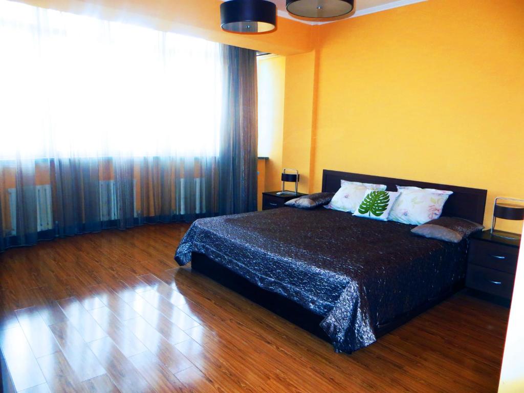 a bedroom with a bed and a large window at Bishkek House Apartament in Bishkek