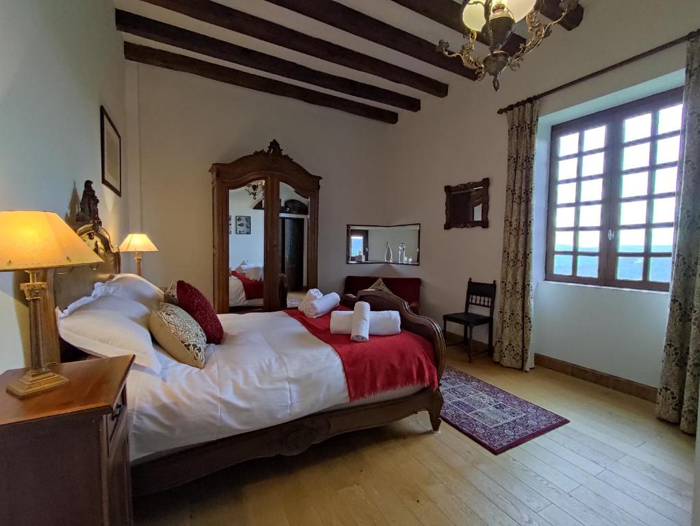 a bedroom with a large bed and a large window at Château de Chauvac - Chambres et table d'hôtes avec vue sur la rivière in Bassignac-le-Bas
