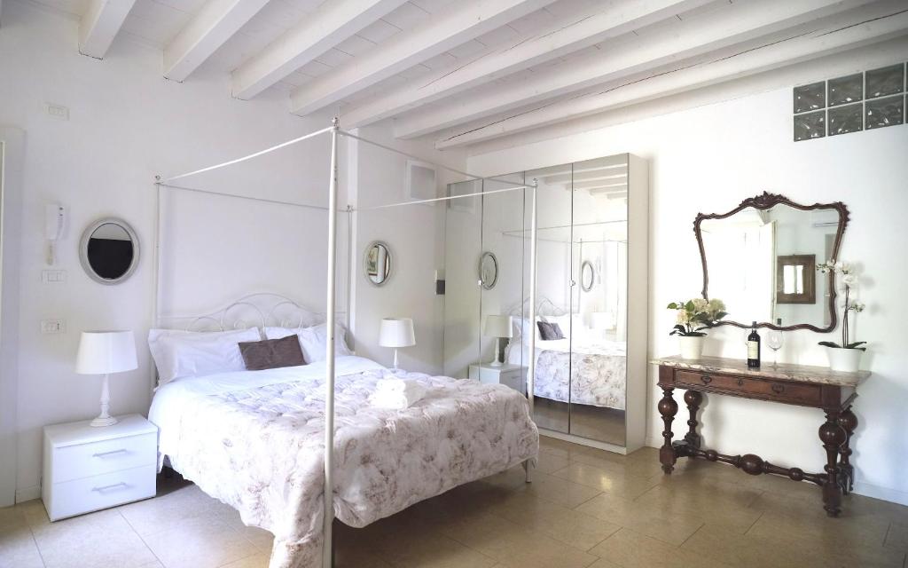 Habitación blanca con cama y espejo en Academia Residence, en Bérgamo