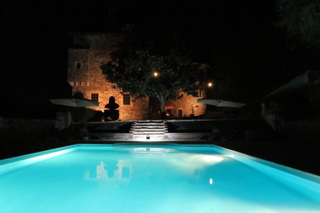 a swimming pool in front of a castle at night at Château de Chauvac - Chambres et table d'hôtes avec vue sur la rivière in Bassignac-le-Bas
