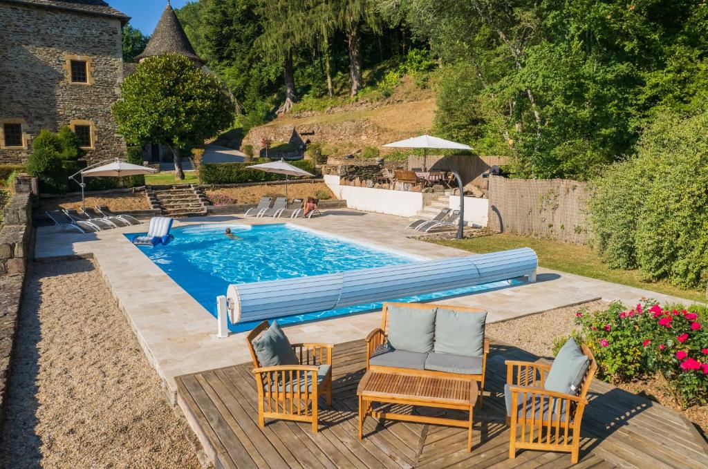 a pool with chairs and umbrellas in a yard at Château de Chauvac - Chambres et table d'hôtes avec vue sur la rivière in Bassignac-le-Bas