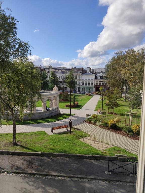 a view of a park with a bench and buildings at Résidence Jehan Froissart in Valenciennes