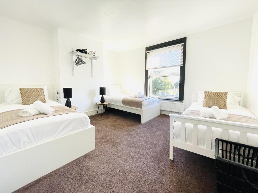 a white bedroom with two beds and a window at Lovely Dog Friendly, 3 Bed Home Sleeps 8, with Parking & Fenced Garden WORK CONTRACTOR LEISURE, JASPER in Cambridge