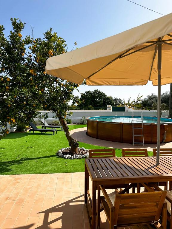 a picnic table with an umbrella next to a pool at Sanzi Country House in Tavira