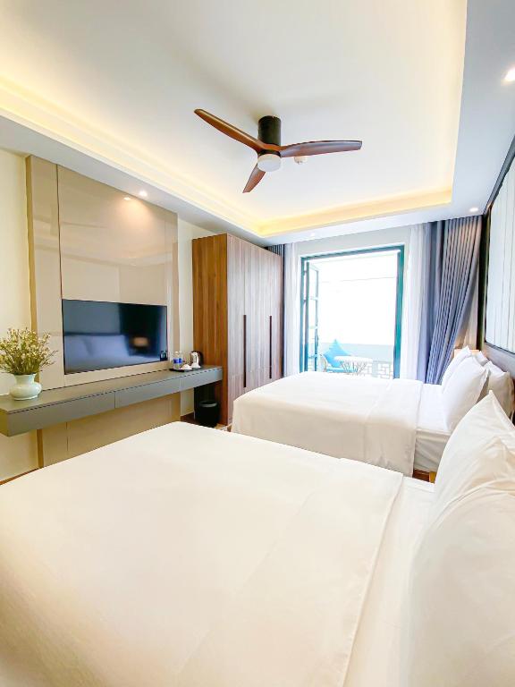 a bedroom with two beds and a flat screen tv at Anna Beach Phú Quốc in Phú Quốc
