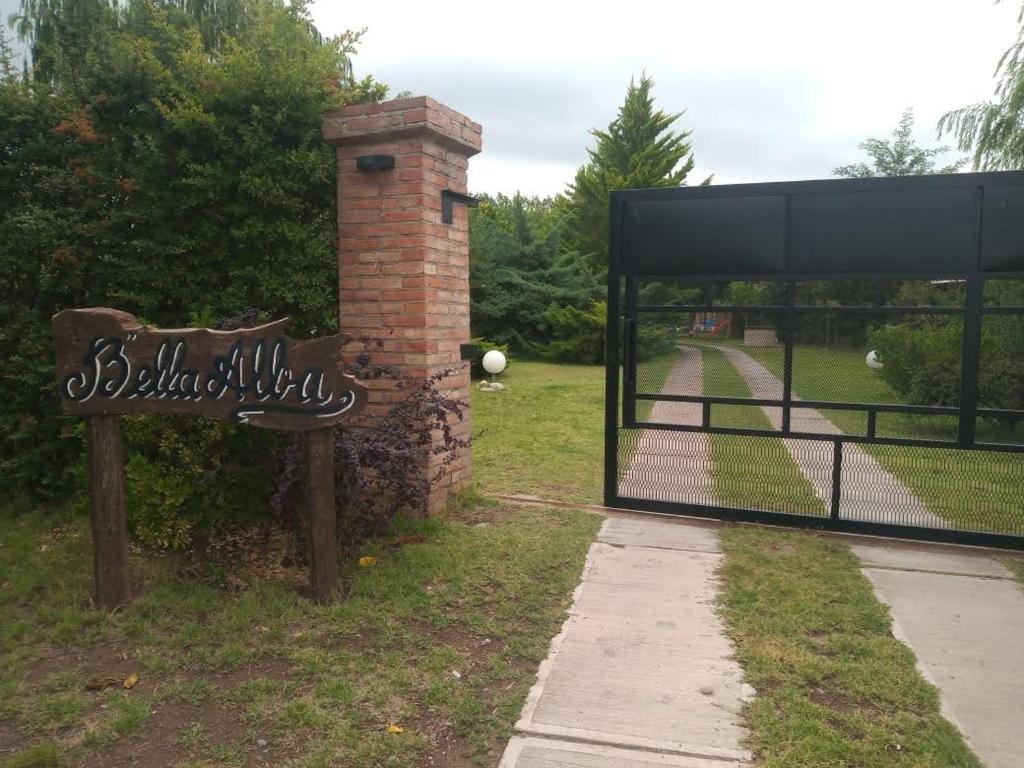 a gate with a sign next to a brick pillar at Cabañas Bella Alba in San Rafael