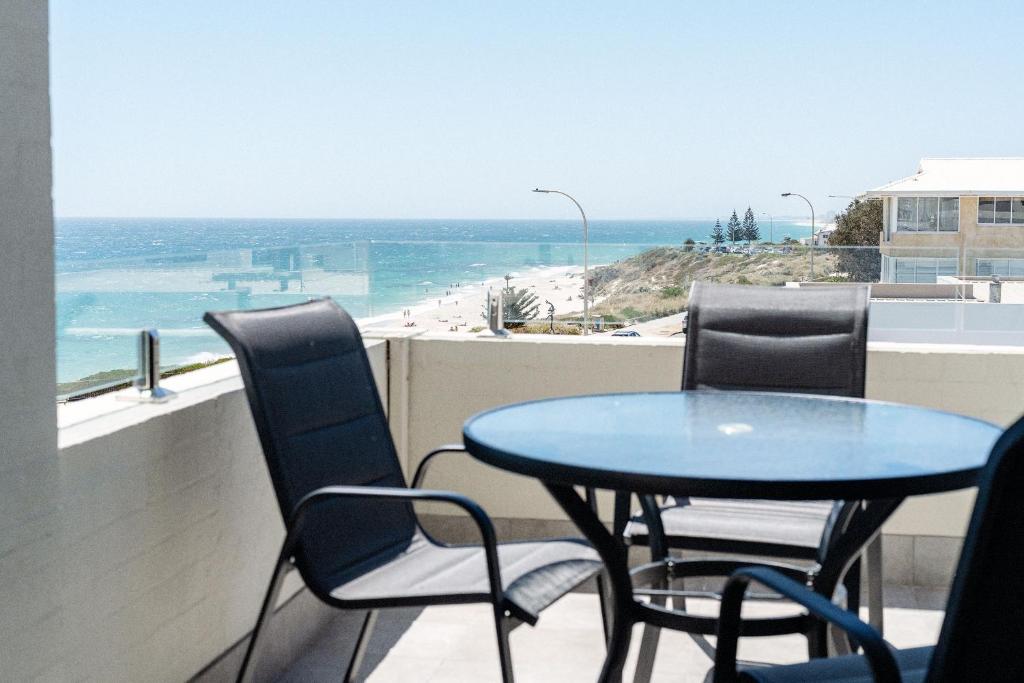 a table and chairs on a balcony with a view of the beach at Cottesloe Beach View Apartments #11 in Perth