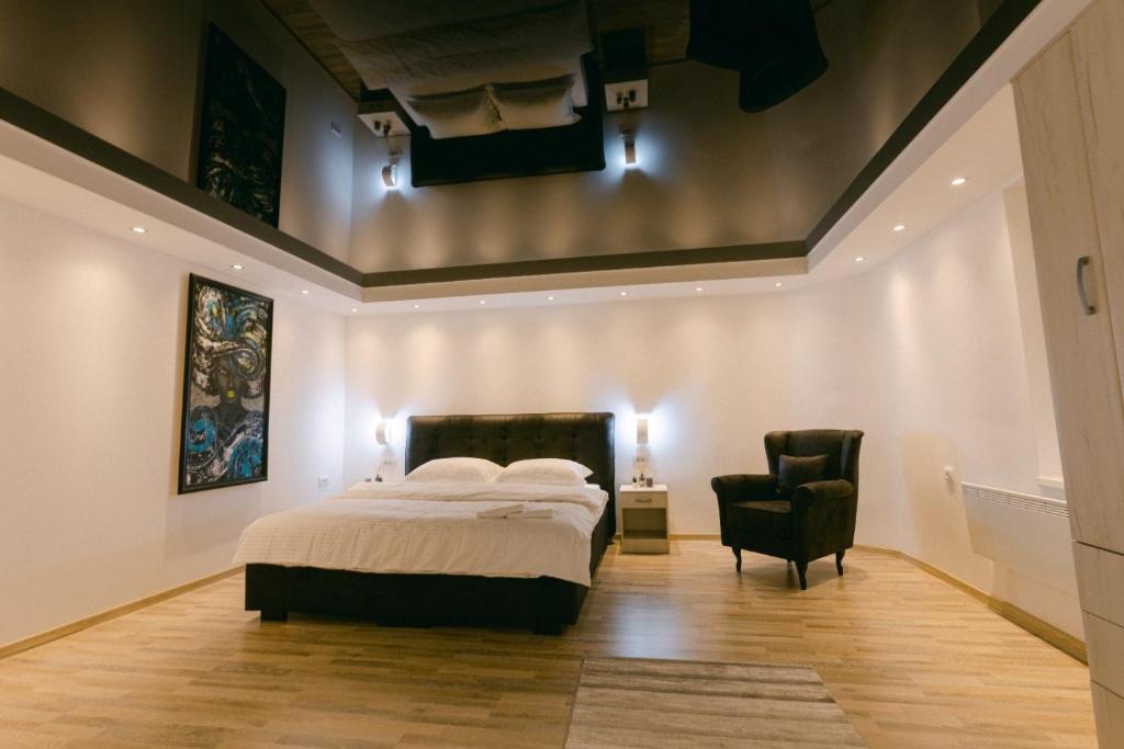a bedroom with a bed and a black chair at Backa idila in Bački Gračac