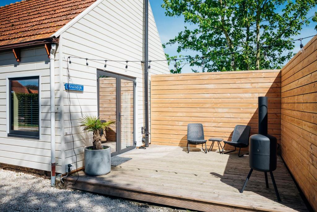 a house with a wooden deck next to a fence at Hello Zeeland - Tiny Houses Groede in Groede