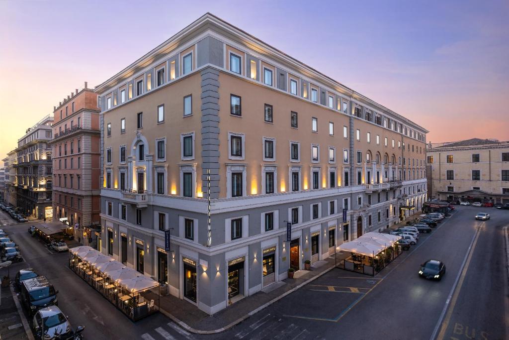 un gran edificio en una calle de la ciudad con coches aparcados fuera en Golden Tulip Rome Piram, en Roma