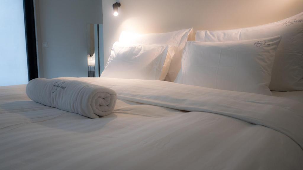 a white bed with a rolled up towel on it at Heirloom Hotels - The Librarian in Ghent