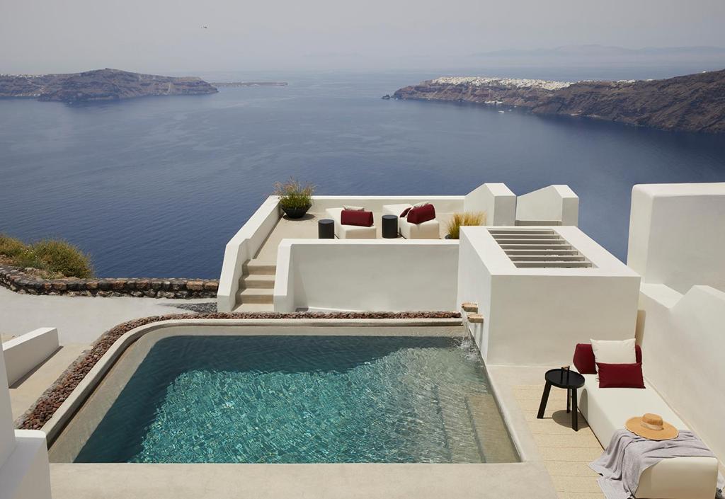 una casa bianca con piscina e oceano di Atoles Retreat a Imerovigli