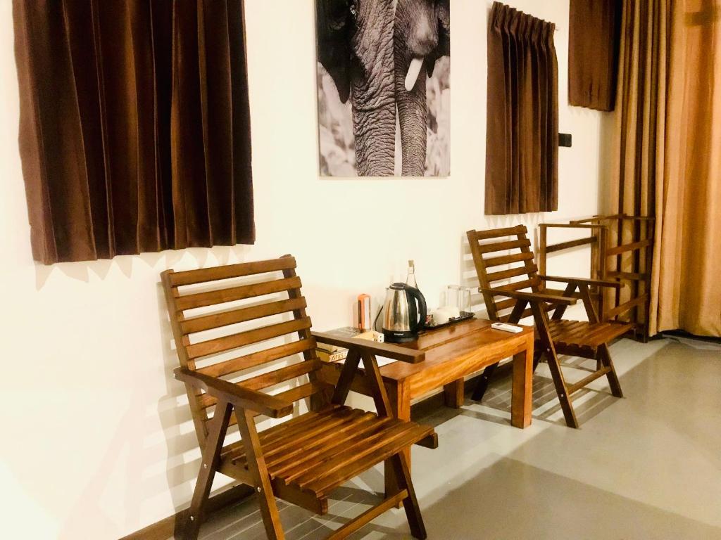 three wooden chairs and a wooden table in a room at Mango Tree House in Udawalawe