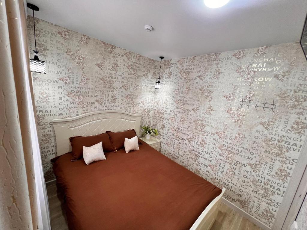 een slaapkamer met een bed en een muur bedekt met behang bij Sport Hotel Terra in Öskemen