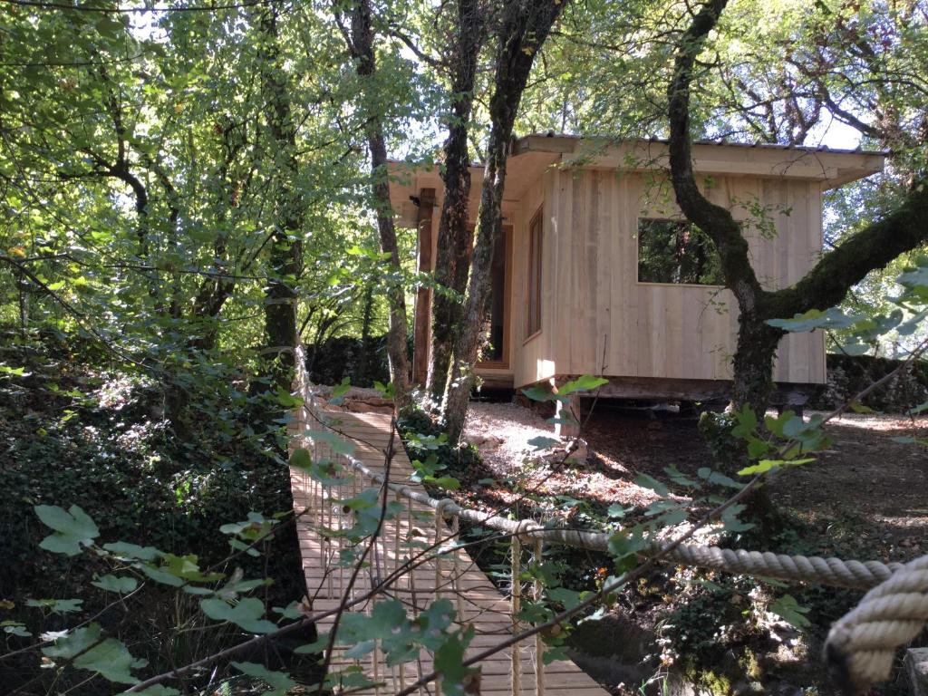 una cabaña en el bosque con un camino que conduce a ella en cabane lodge avec spa privatif, en Livernon