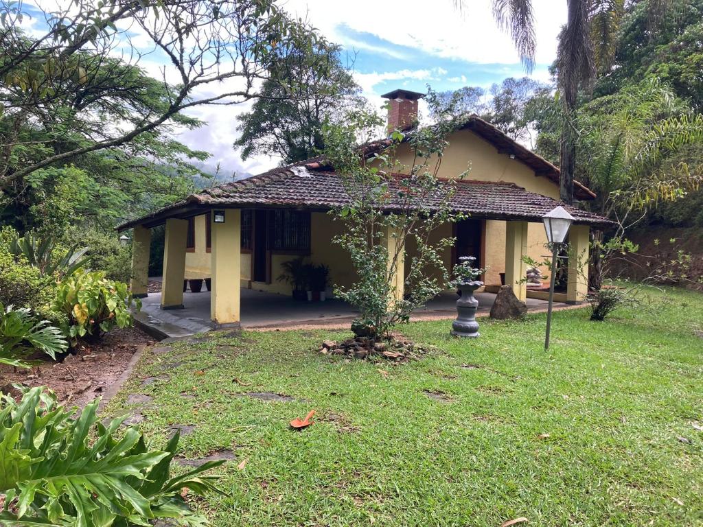 een klein geel huis met een boom in de tuin bij Aconchegante casa nas montanhas de Serra Negra in Serra Negra