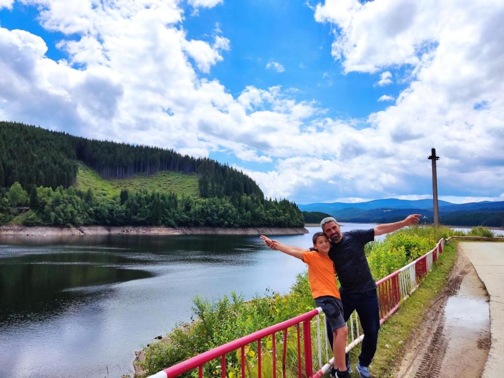een man en een vrouw staan op een hek naast een rivier bij Eden Natural Resort - Transalpina in Căpîlna