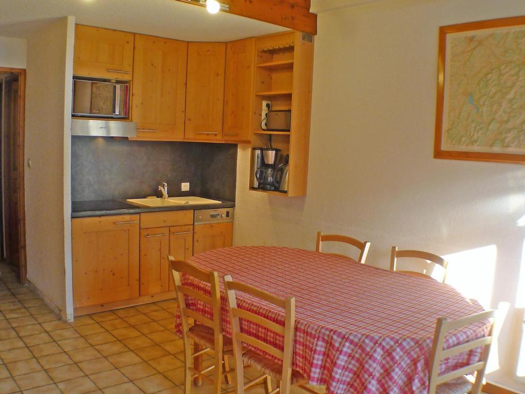 - une cuisine avec une table, une table et des chaises dans l'établissement Charmant appartement 2 pièces mezzanine avec balcon, parking et casier à skis - FR-1-629-38, à Samoëns