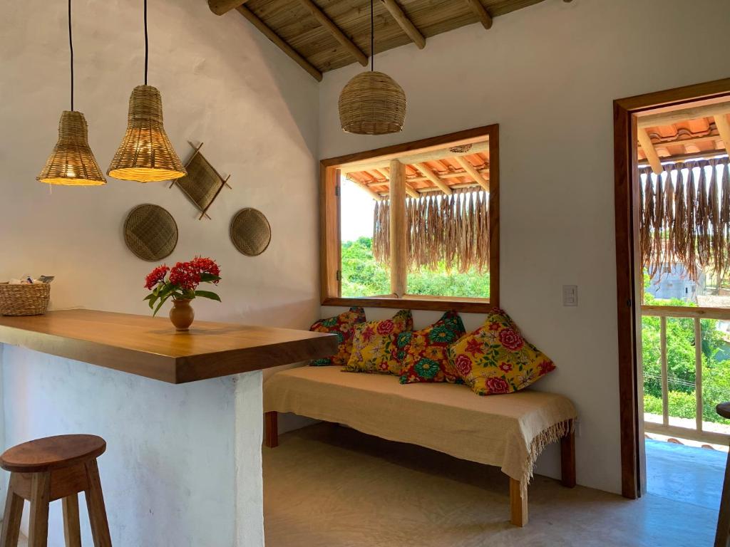 a room with a bench and a table and windows at Casa Jandaia Trancoso - apartamento superior in Trancoso