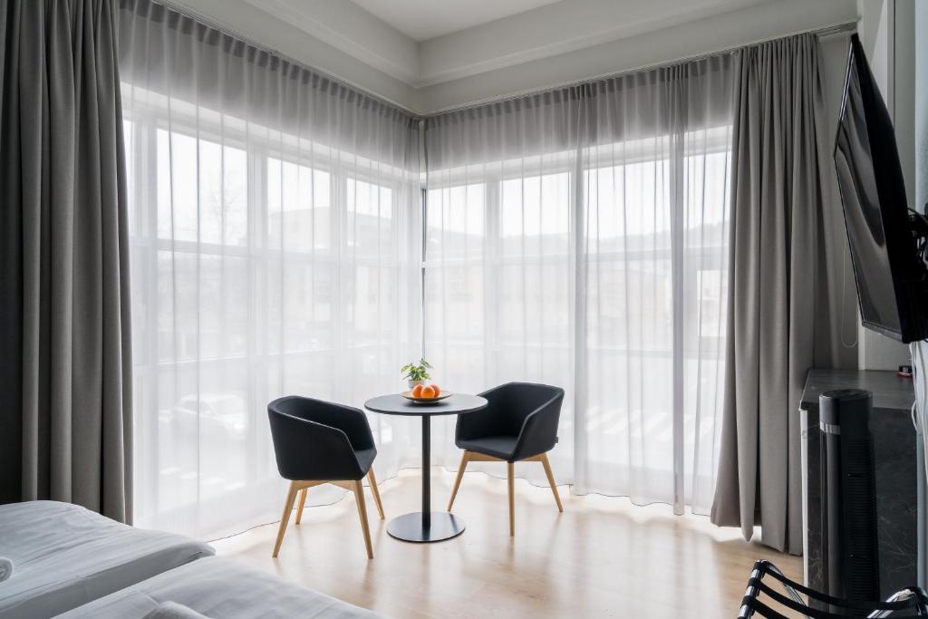 a bedroom with a table and two chairs in front of a window at Hiisi Hotel Lohja in Lohja