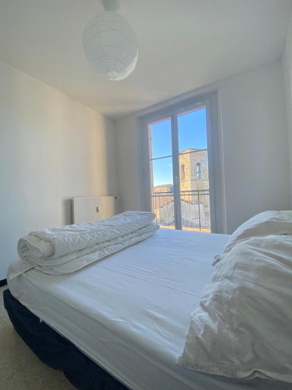 un lit blanc dans une chambre avec une fenêtre dans l'établissement Appartement deux chambres centre historique avec ascenseur et garage, à Manosque