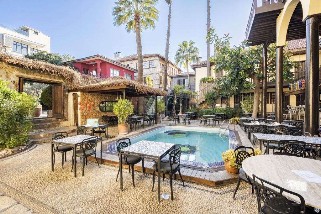un patio extérieur avec des tables et des chaises ainsi qu'une piscine dans l'établissement Cozy Studio Flat near Hadrians Gate, à Antalya