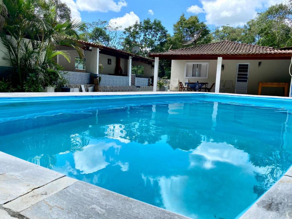 a swimming pool with blue water in front of a house at Chácara das Suculentas in Mairiporã