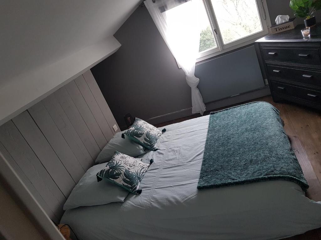 a small bedroom with a bed with pillows and a window at Gîte cocooning avec piscine in Bougé-Chambalud