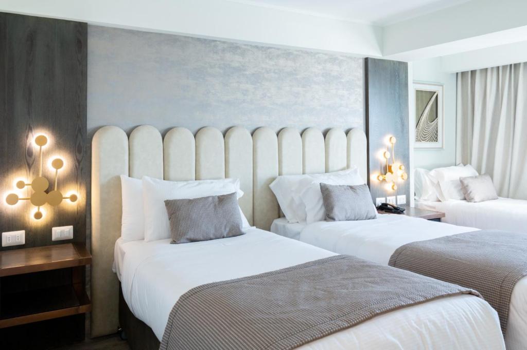 Habitación de hotel con 2 camas con sábanas blancas en Hotel HW High Wellness, en Santiago