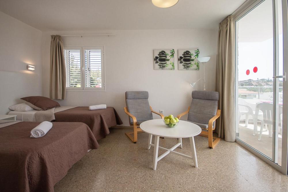 a hotel room with two beds and a table and a window at Apartamentos Tarahal in San Agustin