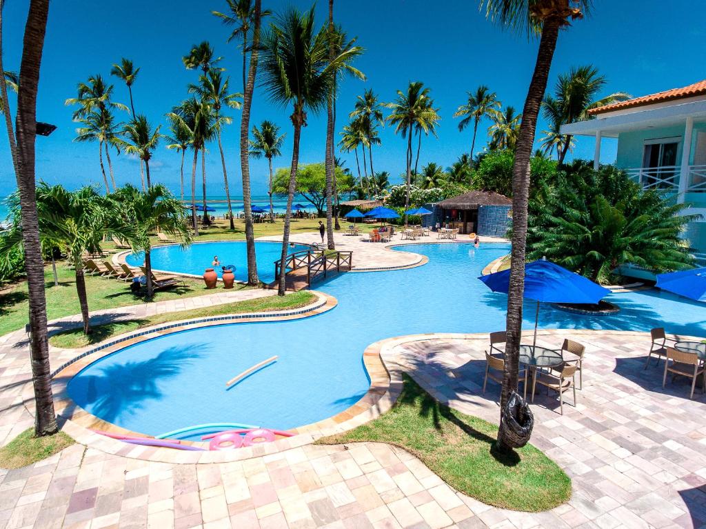 a swimming pool with palm trees and a resort at Baía Branca Beach Resort in Tamandaré