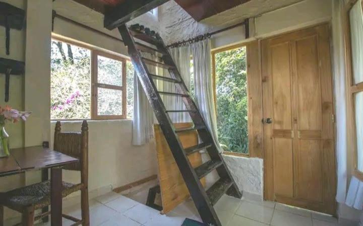 - un escalier en colimaçon dans une chambre avec une table et une fenêtre dans l'établissement ex hacienda molino de pedreguera, à San Roque