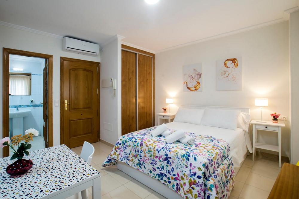 una camera bianca con letto e tavolo con sidro. di Apartamentos AMAT - Only Adult - Playa El Bajondillo a Torremolinos