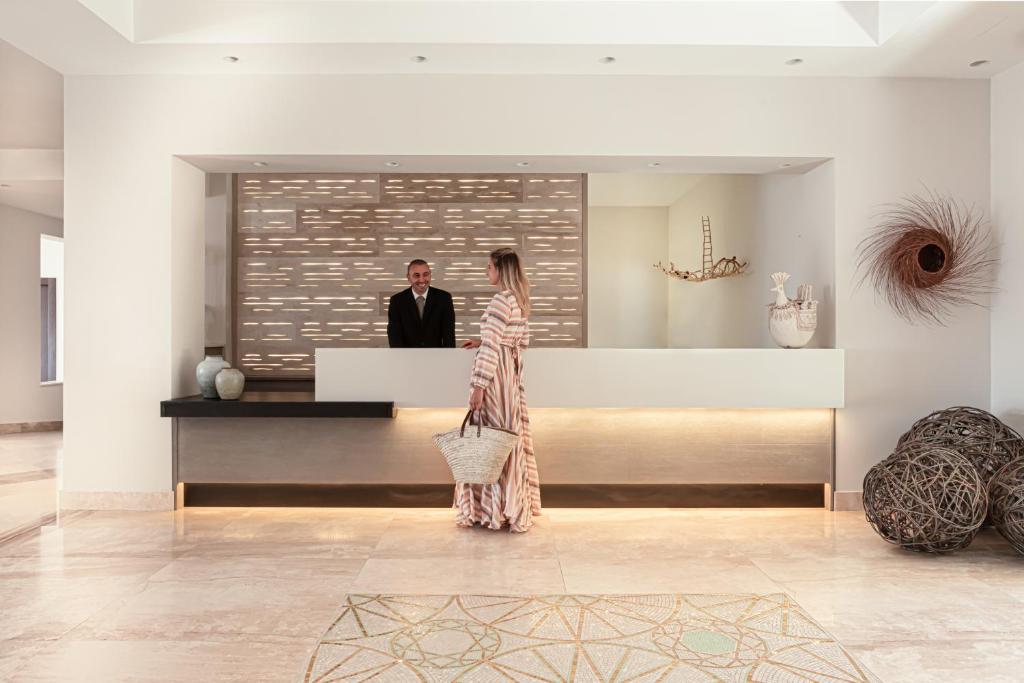 a woman in a dress standing in a lobby with a man at Cala Cuncheddi - VRetreats in Murta Maria