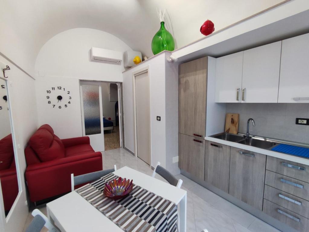 una cucina con divano rosso e tavolo in una camera di La dimora nel sottano alla strada a Polignano a Mare