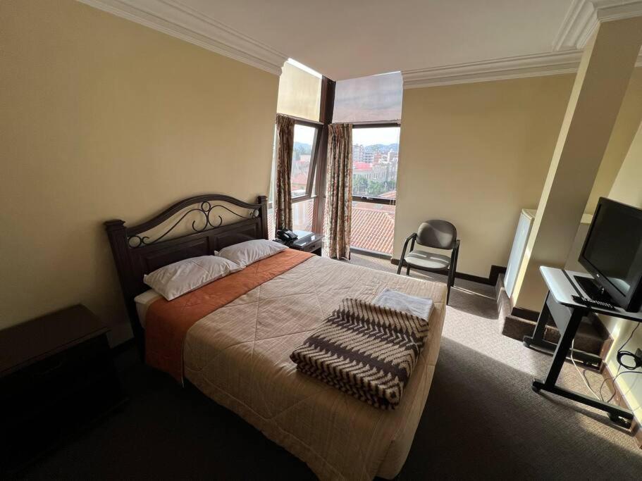 1 dormitorio con 1 cama, TV y ventana en Habitación Privada-Corso Cbba 23, en Cochabamba