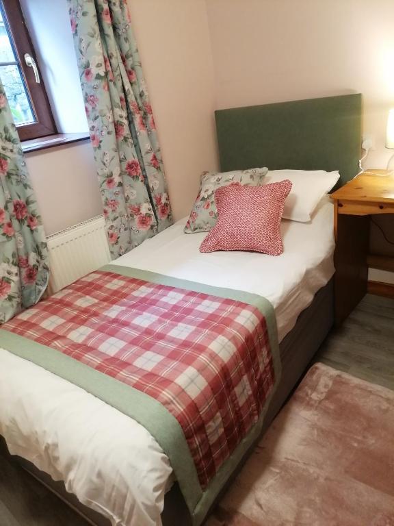 a small bedroom with a bed with a red pillow at Stag Coach House in Carmel