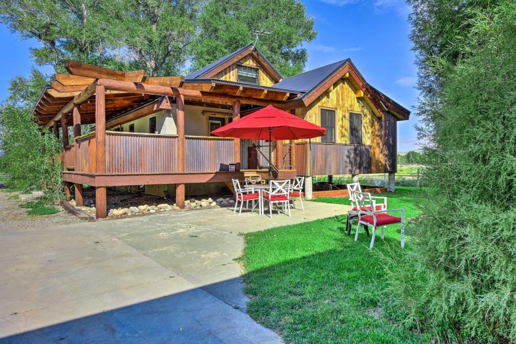 um chalé de madeira com uma mesa, cadeiras e um guarda-sol em Gunnison Retreat about 3 Mi to Western CO University! em Gunnison