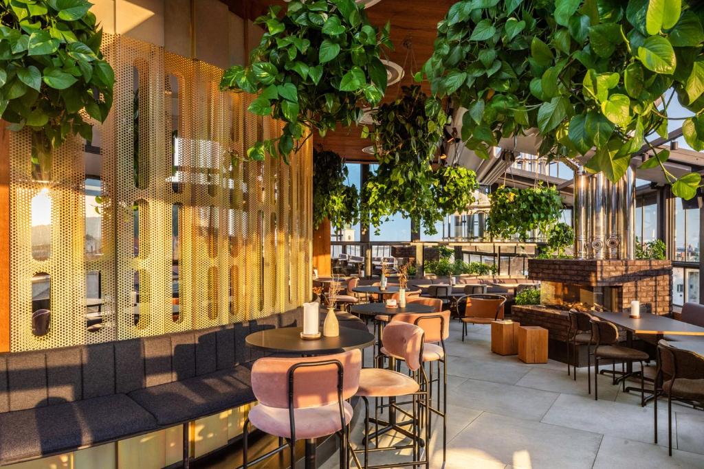 a restaurant with tables and chairs and plants at Hotel Rum Budapest in Budapest