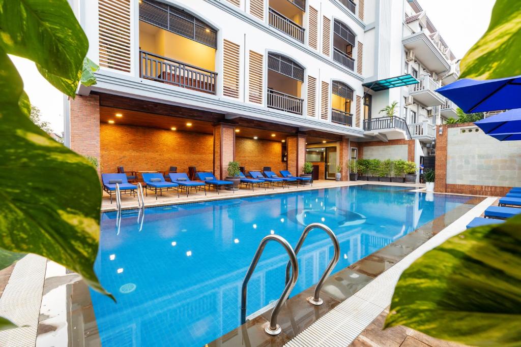 Blanc Smith Hotel في سيام ريب: مسبح وكراسي زرقاء ومبنى