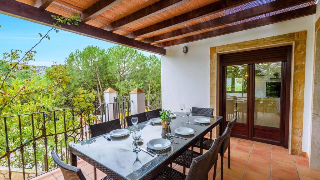 y patio con mesa de comedor y sillas y balcón. en Lake view villa Iznájar by Ruralidays en Iznájar