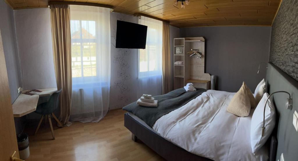 Schlafzimmer mit einem Bett, einem Schreibtisch und einem TV in der Unterkunft Hotel Bartenwetzer vormals Ellenberger in Melsungen