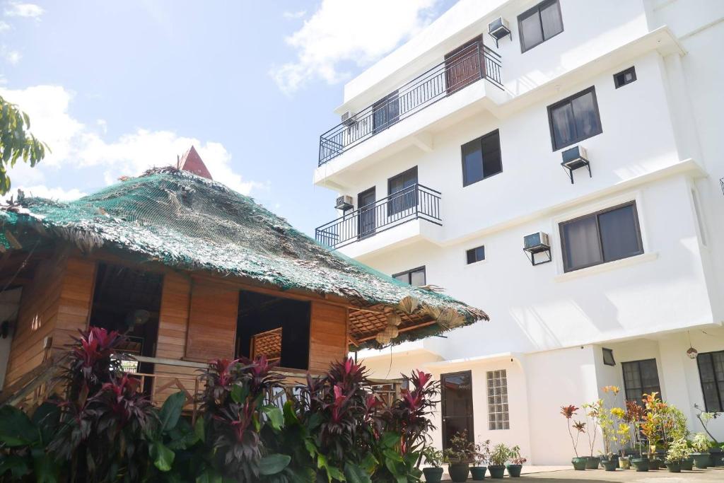 a house with a thatched roof and a building at SaSa Pension House in Catarman