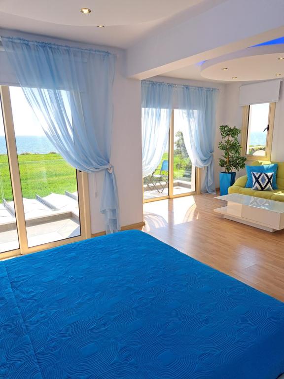a bedroom with a blue bed with a view of the ocean at Villa Sunshine in Mazotos