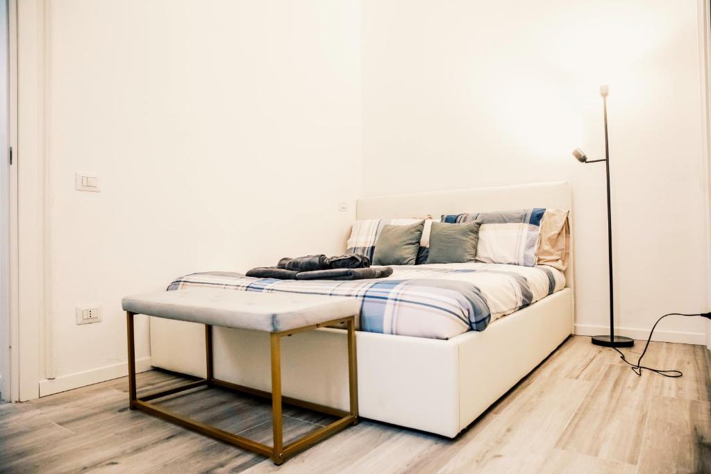 a white bed with a bench in a room at Stazione-Centro Luminoso Bilocale in Brescia