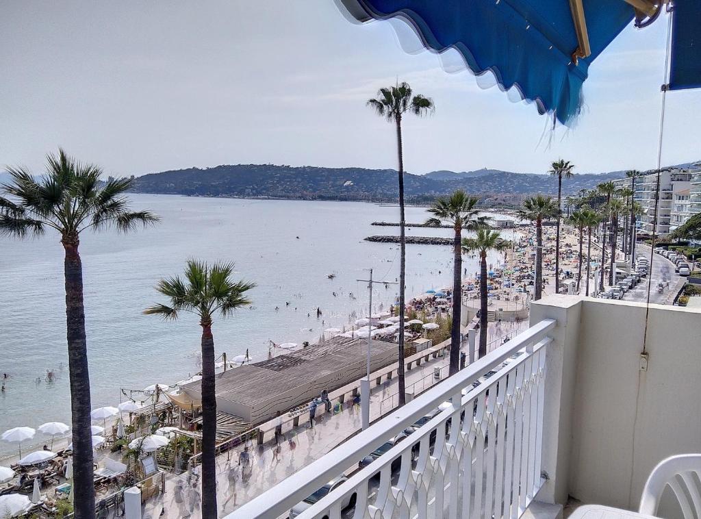 d'un balcon avec vue sur la plage et les palmiers. dans l'établissement Résidence de la mer, à Juan-les-Pins