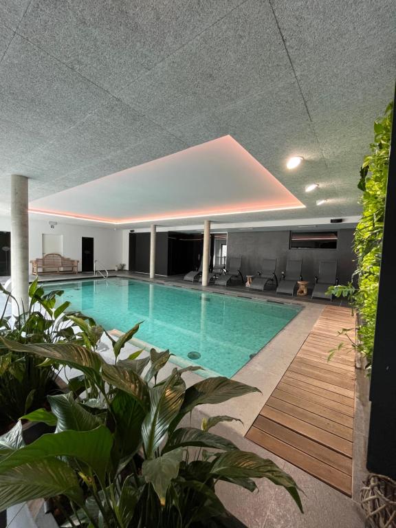 a swimming pool in a building with plants at Hôtel WELLNESS EAU DE ROCHE Durbuy in Durbuy